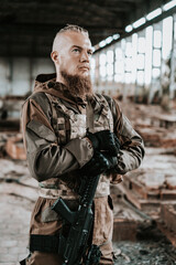 a male military soldier in an abandoned building with a gun poses, shoots and takes aim