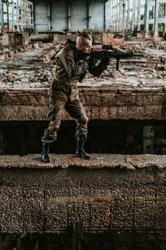 a male military soldier in an abandoned building with a gun poses, shoots and takes aim