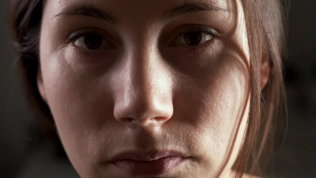 Sad attractive brunette girl looks wearily at the camera and blinks. The concept of insomnia and illness