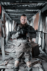 a male military soldier in an abandoned building with a gun poses, shoots and takes aim