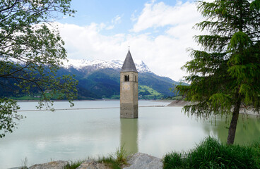 Fototapeta na wymiar a picturesque view of lake Resia and the sunken church steeple of Lago di Resia in the Curon region (Vinschgau or Curon, South Tyrol, Italy) 