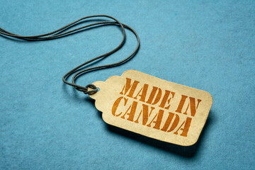 made in Canada sign - red stencil text on a paper price tag against grunge wood