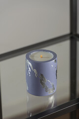 Round candle holder with abstract smudges, blue concrete with silver flame. selective soft focus