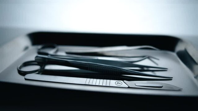 Medical instruments in steel tray on table for surgery. Preparing of surgical tools for a operation. Scalpels and forceps and tweezers. Surgery or emergency case and ambulance or treatment concept.