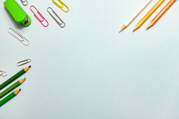Paper clips and pencils on blue background, office concept with negative space