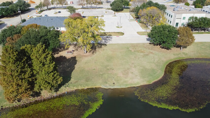 Fototapeta na wymiar Top view office building and commercial warehouse near algae blanket lily pad pond in Carrollton Texas, USA