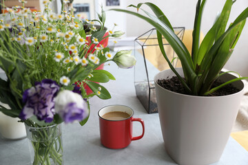 Red mug with coffee with milk on the table in interior