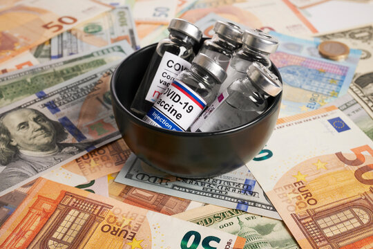 Covid vaccines in ceramic bowl - photo on money bank notes. Coronavirus vaccine vials in black ceramic is placed on money bank notes. Euro and dollar banknotes as background for Covid-19 inoculation.