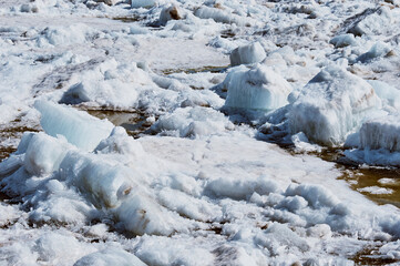 Ice drift on the Amur River. Melting ice floes in spring. A heap of blocks and fragments. Sunny day.