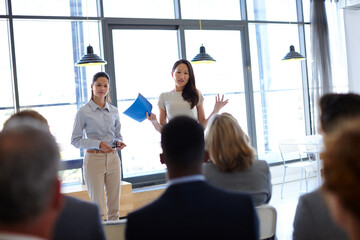 Any ideas. Shot of two young businesswomen giving a presentation to their coworkers.