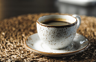 a mug with freshly brewed coffee stands on a wicker stand, blurred background, side view