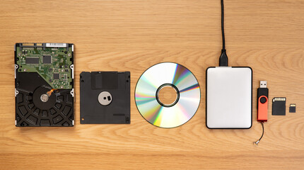 Data storage devices such as CDs, hard drives, pen drives and other, top view on a wooden background