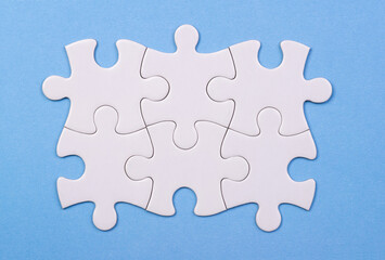 Blank white jigsaw puzzle pieces on blue background
