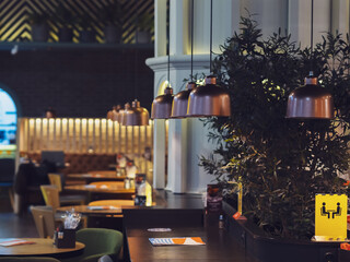 Modern interior of the restaurant with metal lamps above a wooden counter with olive wood. Selective focus