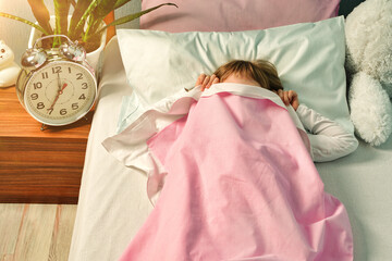 Sleeping child cover face with blanket and doesn't want to wake up in the morning