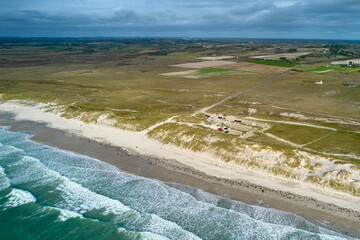 Aerial view of french beach in the brittany. Parking for campers behind the dune. Sea with waves....