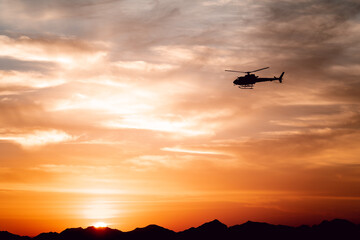 sunset landscape with rocky mountains silhouette with helicopter
