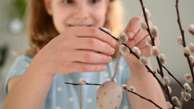 4K of smiling pretty girl hanging easter eggs on twing branches