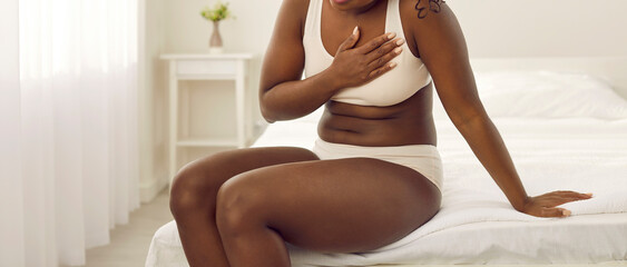 African American woman suffering from heart disease. Young black lady in white underwear suddenly...
