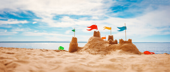 Sand castle with colourful flags on the beach of the sea