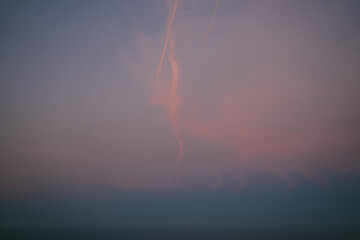 Winding plane contrail on the beautiful gradient sky during sunset in Basque Country coast