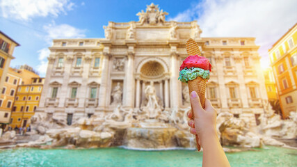 Famous landmark fountain di Trevi in Rome, Italy during summer sunny day with italian ice cream gelato in the foreground.
