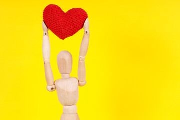 wooden man with a red heart in his hands on a yellow background