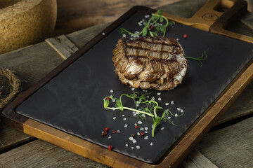 filet mignon steak lezhin on a stone and wooden stand, decorated with microgreens and large salt...