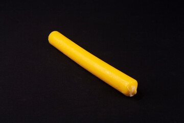 A bright orange candle lies on a table with a black cloth