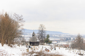 Old Saxon cemetery near wooden church in the winter, church historical monument located in a beautiful and quiet village Sinca Noua, Transylvania, Brasov