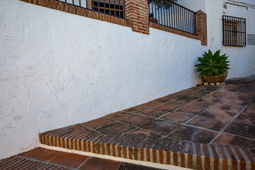 Frigiliana, Malaga, Spain. Sunny spring day street travel view. Potted succulent plant on brick patio