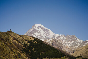 A beautiful mountain landscape with a blue sky. Snow-capped peak of Mount Kazbek in Stepantsminda Georgia