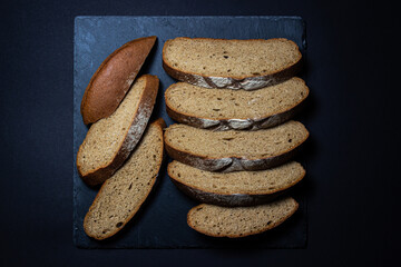 Bread on a black background. Sliced fresh homemade bread in a dark dish. Traditional food