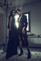 Two women wear elegant fashion clothes posing indoor.