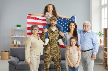 Portrait of a military father and his big happy family with an American flag in his hands. Grandparents, soldier's wife and daughters looking at the camera smiling. Concept of military service.