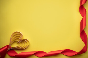 paper heart on a yellow background with a red ribbon. place for text