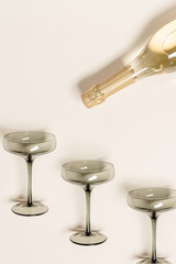 Champagne or sparkling wine poured from bottle with glasses tinted grey glass, creative flat lay,...