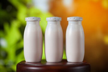 Natural liquid yogurt with probiotics in small plastic bottles on wooden table on background of green trees on a sunny day. Healthy, balanced diet food, healthy breakfast, dairy products.