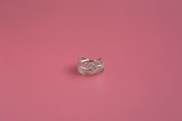 Jewelry on pink background close up, silver ring with precious stones

