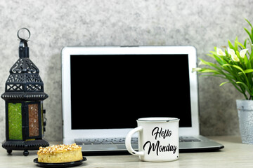 laptop with empty screen for your logo or you work with lilies flowers pot and hello Monday on cup...