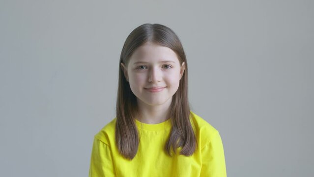 Blonde teenager girl in a yellow T-shirt smile against the background of a white wall