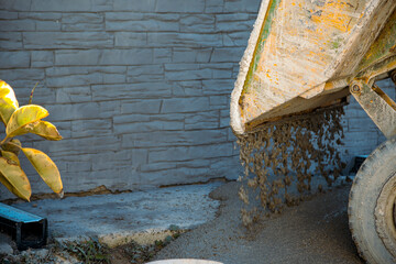 Dumper machine unloading concrete on the sidewalk to cover the drains with a small ficus sticking...