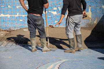 Workers considering the best way to carry out their work, refilling the pool to prepare it for the summer.