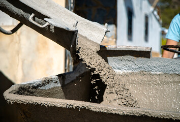 Mouth of the concrete mixer truck unloading the concrete inside the Dumper to continue with the work