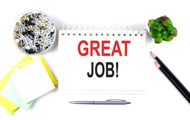 GREAT JOB text on notebook with office supplies on white background