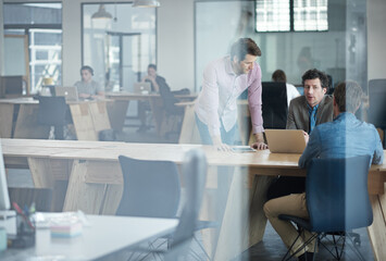 Obraz premium Sharing ideas. Through the glass shot of a group of colleagues working together in an office.
