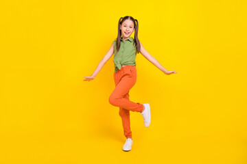 Photo of funny childish preteen girl dressed green top walking smiling isolated yellow color background