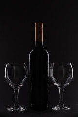 Wine bottle and two glasses positioned symmetrically against a solid black backdrop, highlighting minimalistic design.