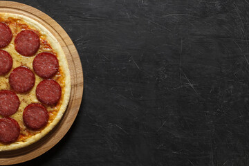 Pepperoni pizza whole uncut, on side on dark background with space to copy text.