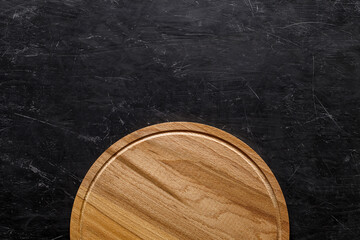 Wooden round cutting board for pizza, top view dark background, with space to copy text.